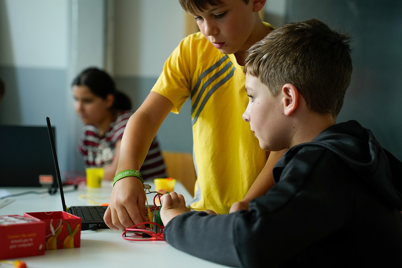 2 Kinder tüfteln an Steckverbindungen an einem Notebook